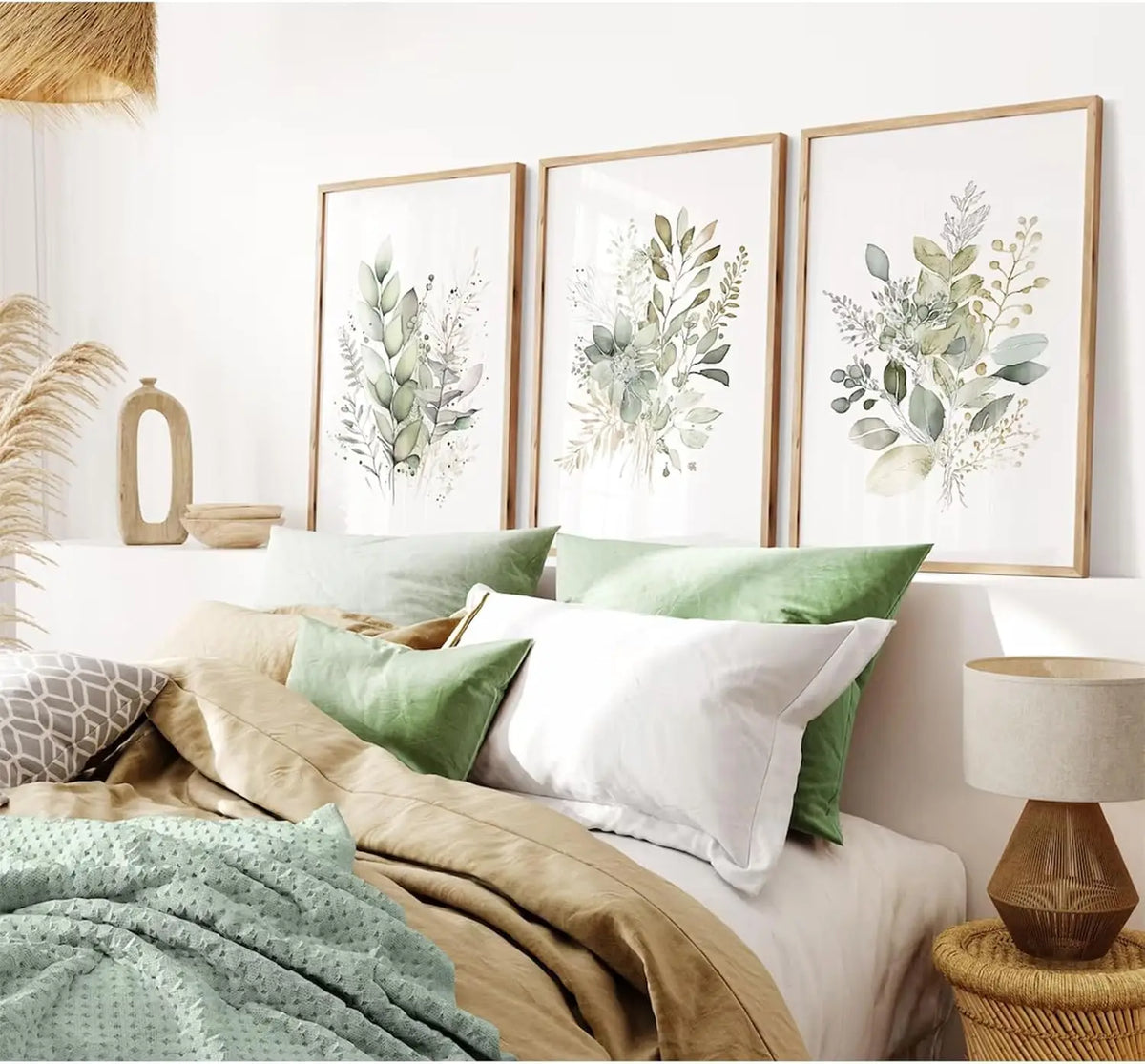 Three framed watercolor botanical prints featuring green and white wildflowers displayed on a bed.
