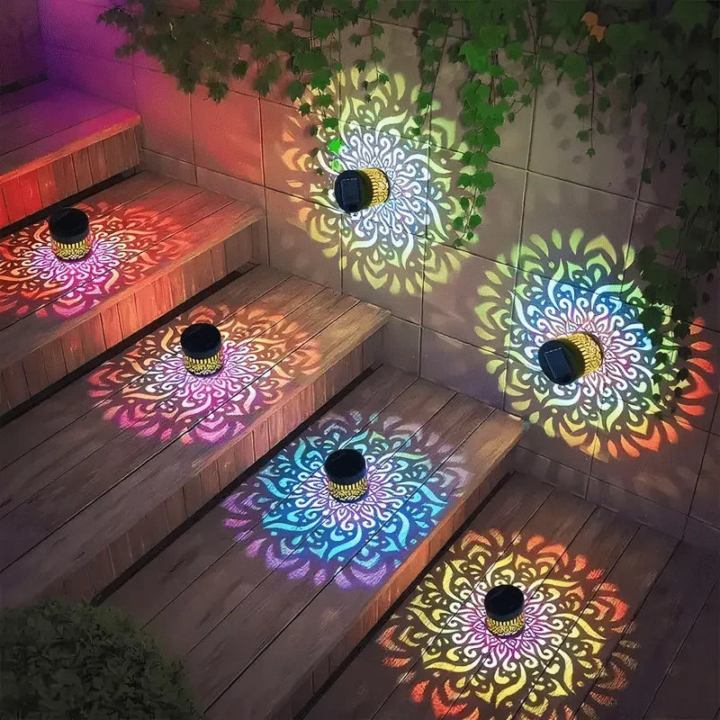 A solar-powered mandala wall lantern illuminates a patterned light display on wooden steps and a stone wall.