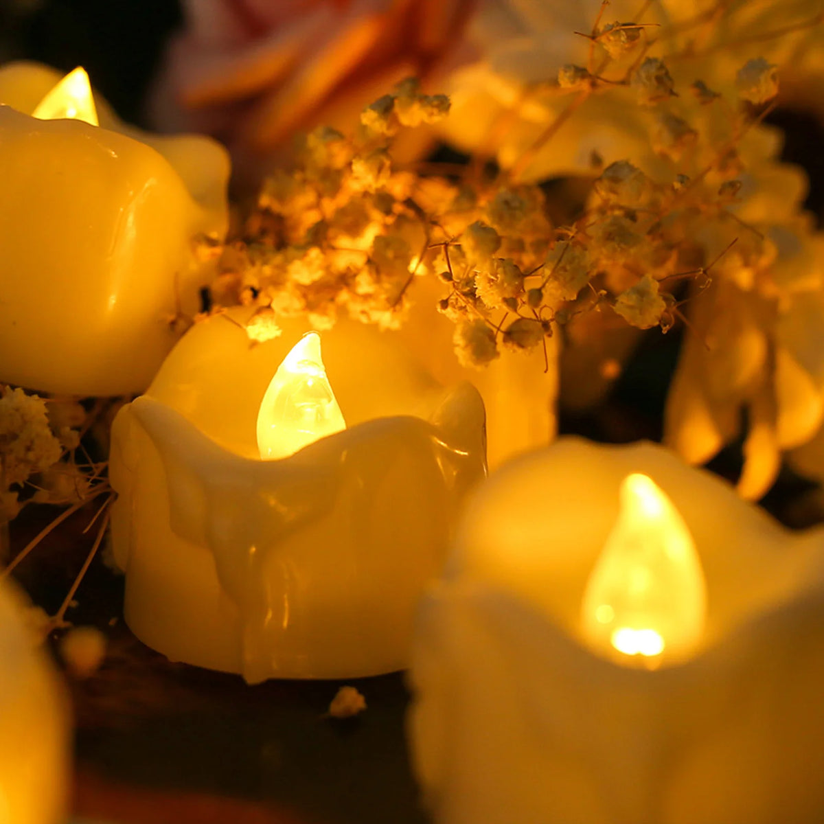 Close-up of glowing yellow LED tealight candles casting a warm light on surrounding foliage.