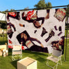 A large tapestry featuring hip-hop culture imagery, including figures and patterns, displayed outdoors on a green lawn.