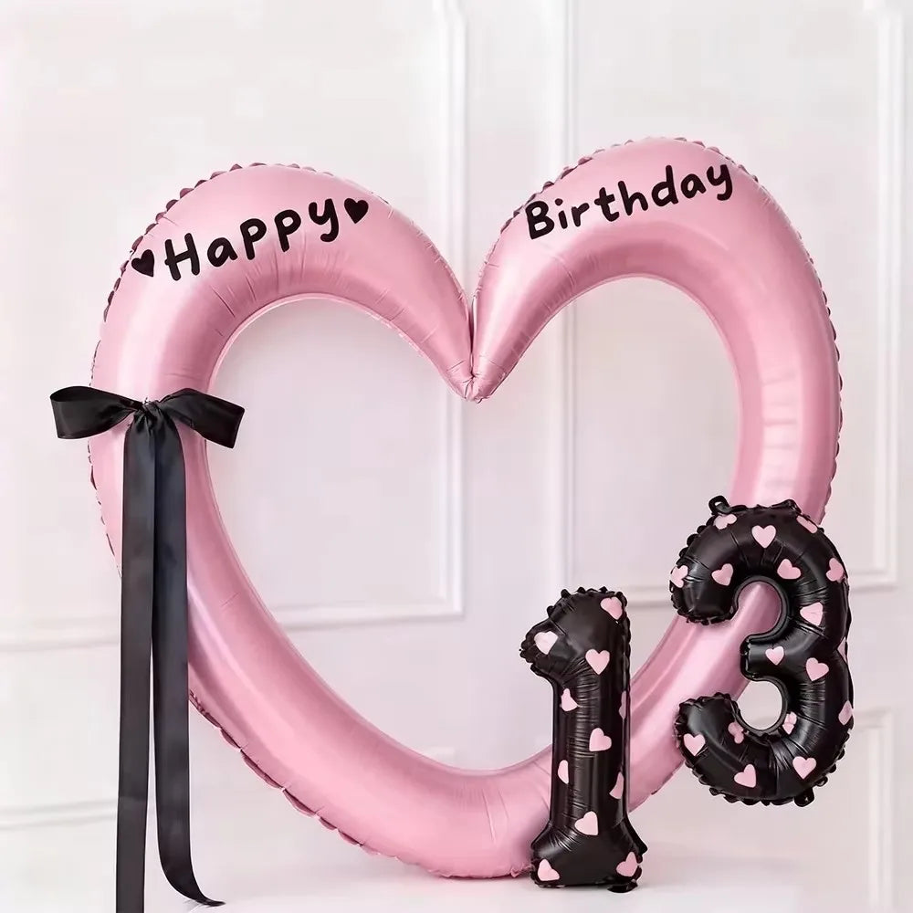 Pink heart-shaped balloon decoration with Happy Birthday text and black ribbon