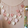 Handwoven pink leaf tassels hanging from a string on a wall