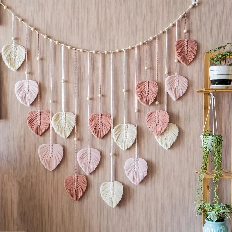 Handwoven pink leaf tassels hanging from a string on a wall