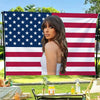 A woman posing in front of a large American flag backdrop.