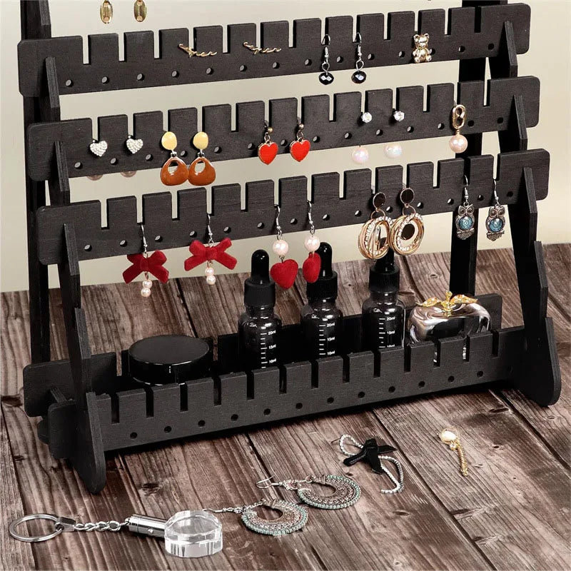 A black wooden earring organizer rack displaying various dangle and stud earrings.