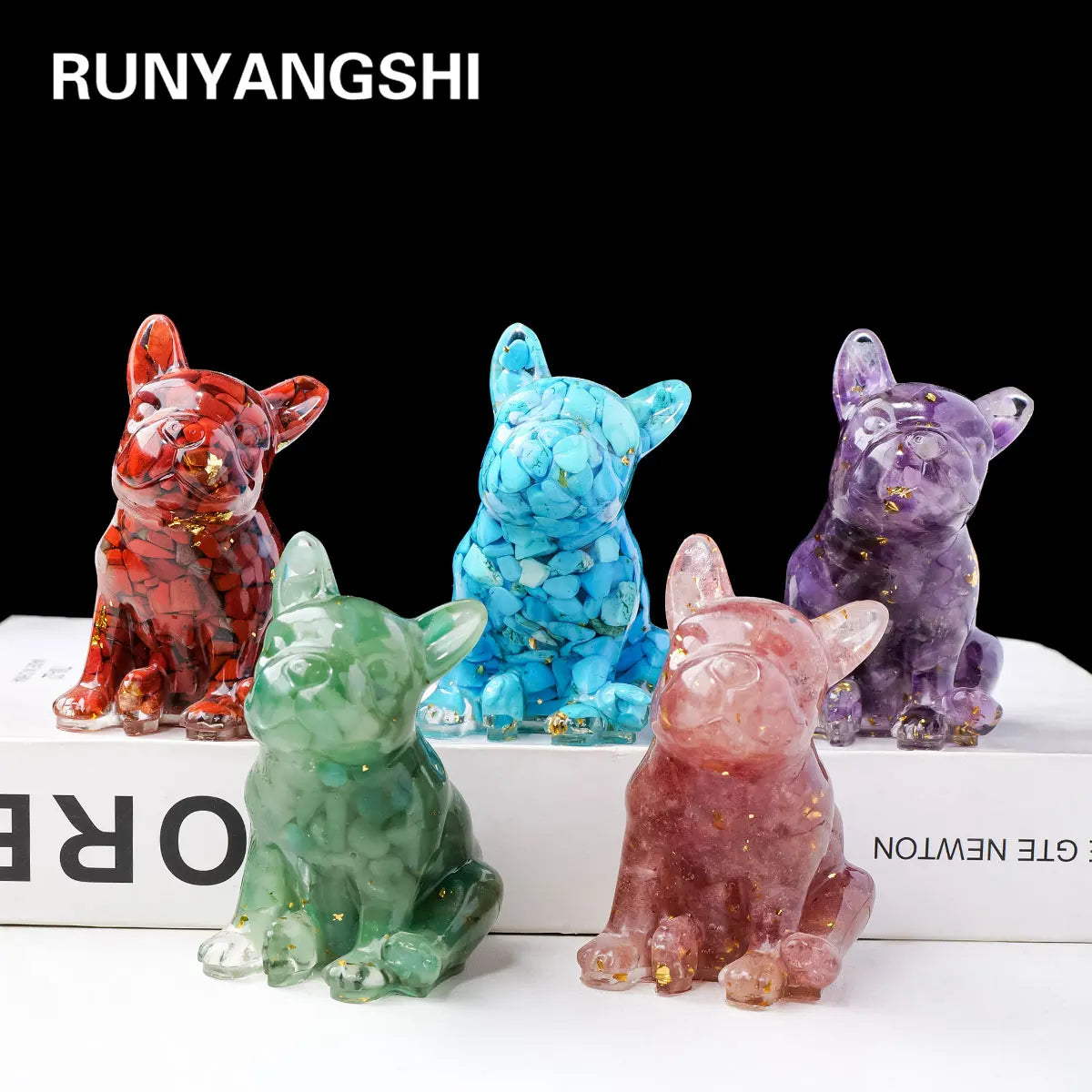 A set of three natural crystal dog statues in red, blue, and purple sitting on a white surface.