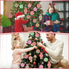 A man and a young girl decorate a Christmas tree with rustic wooden peppermint candy ornaments.