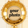 A golden foil balloon shaped like a heart, featuring a circular label for a custom photo.