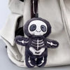 A dark gray mummy skeleton plush keychain is visible inside a light beige fabric bag.