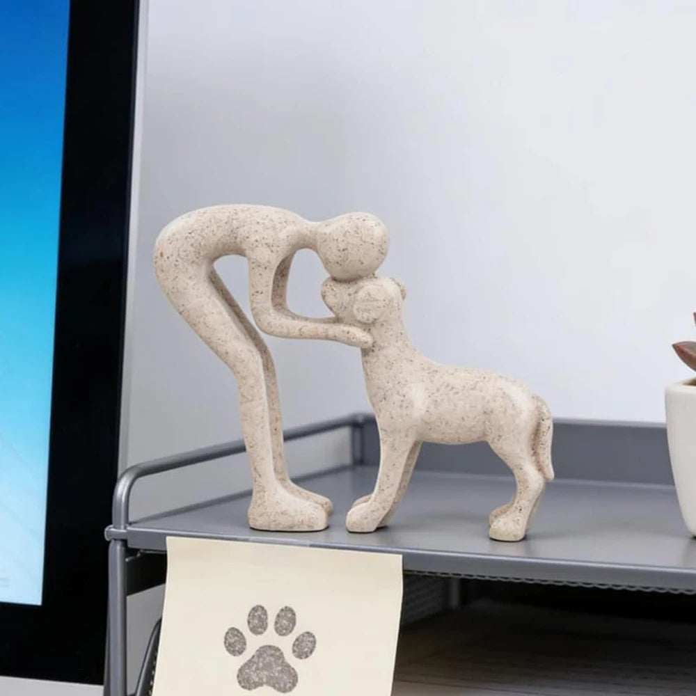 A beige sculpture depicting a human and a dog embracing, displayed on a gray shelf.