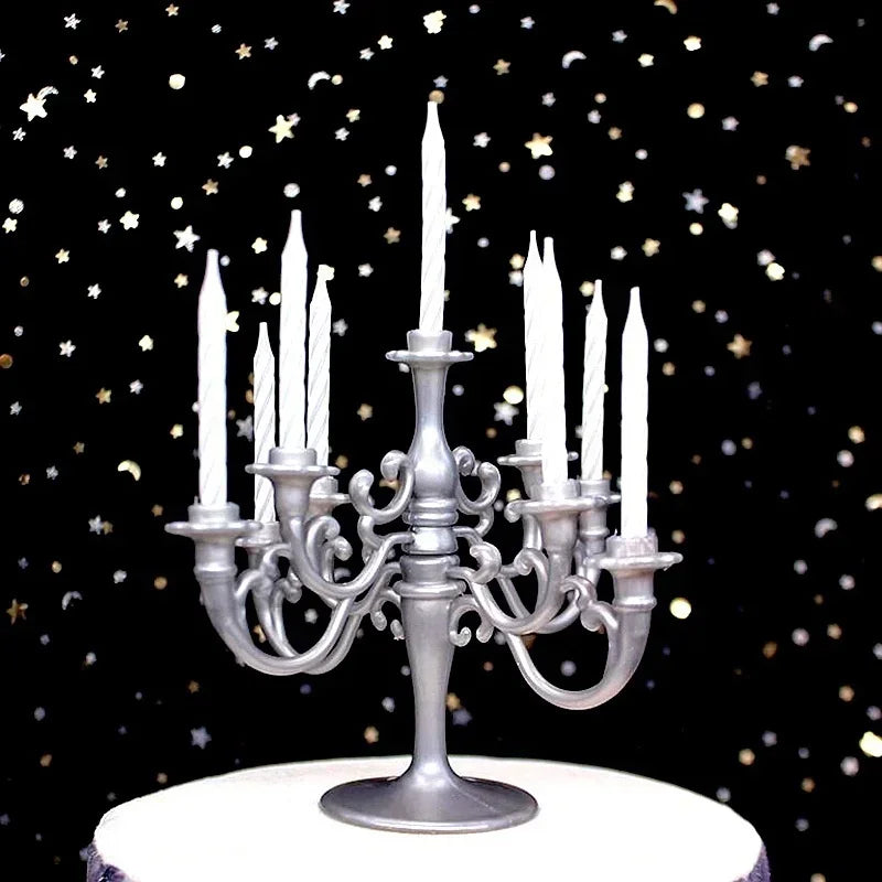 A silver candelabra holding nine white candles on a white cake with scattered gold and silver stars.
