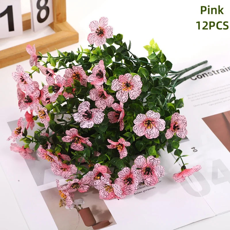 Pink artificial daisy flower bundles with green leaves displayed on a white background.