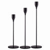 A set of three elegant black metal candle holders with tall, slender arms.