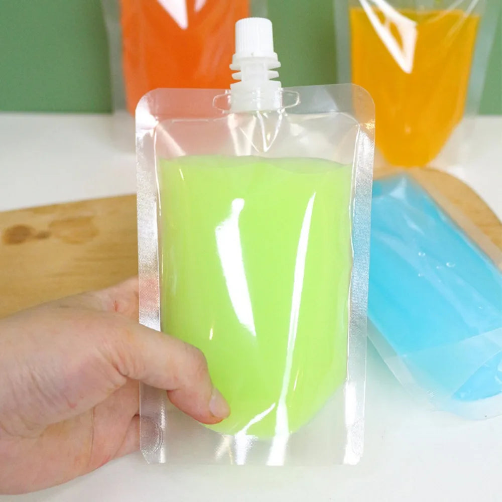 A hand holds a clear pouch filled with bright lime green liquid, demonstrating reusable squeezable drink pouches.