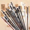 A collection of character-inspired metal and resin magic wands displayed against a light background.