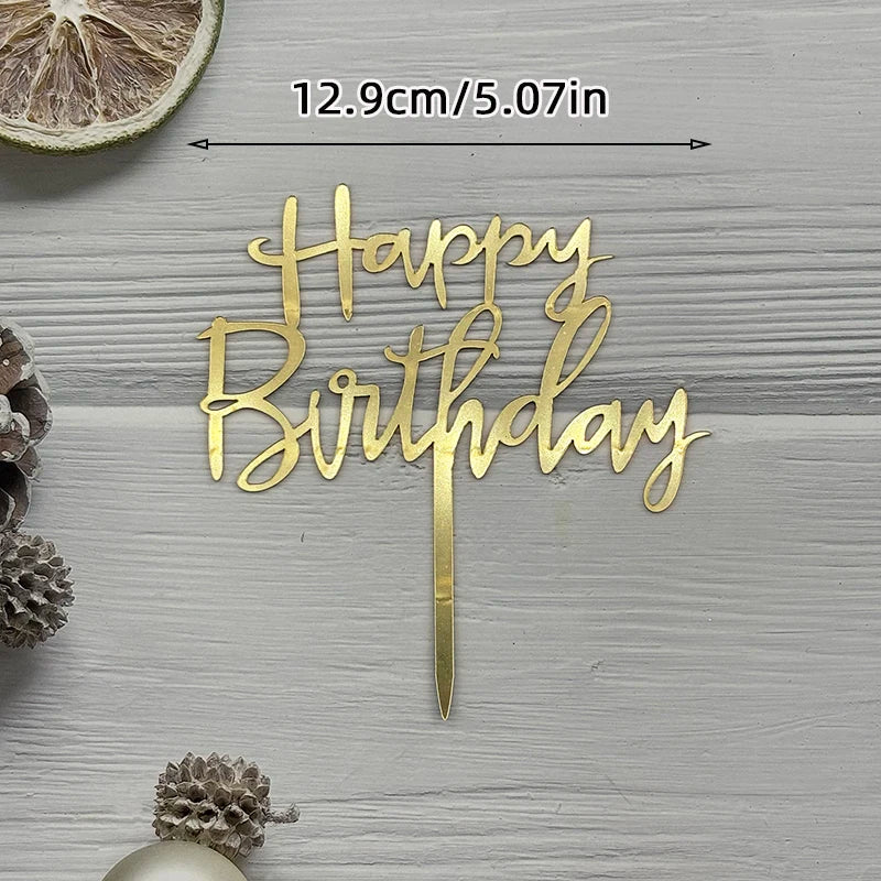 Gold acrylic birthday topper with the words Happy Birthday on a wooden surface