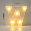 A glowing white LED letter light sign shaped like the letter W, illuminating a room.