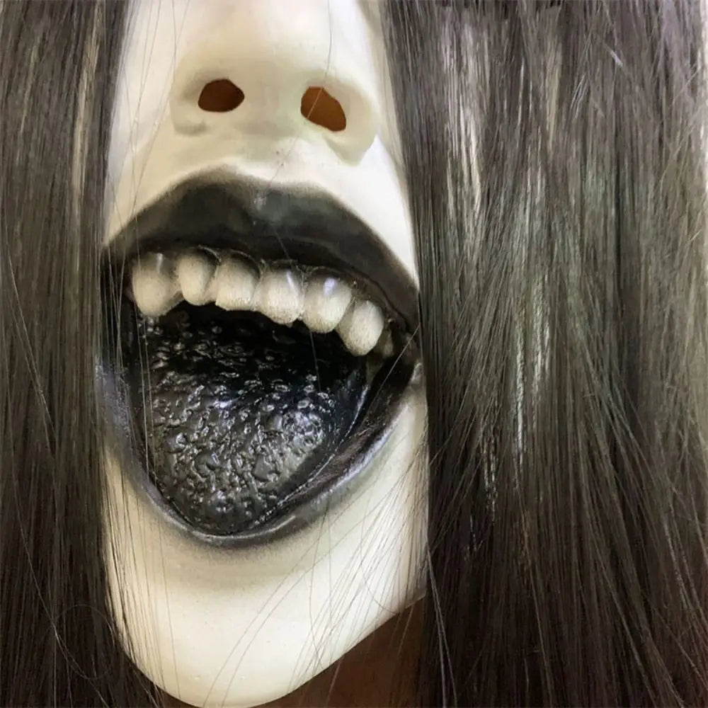 A realistic latex horror mask with pale skin and long black hair showing an open mouth.