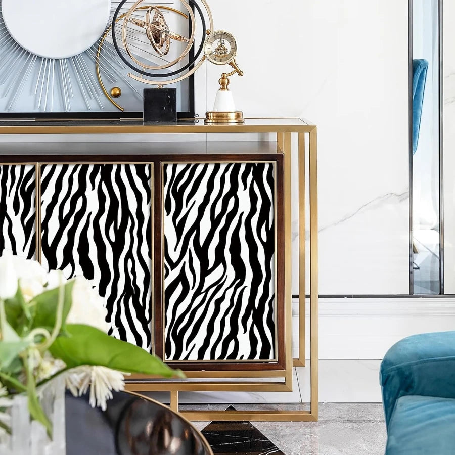 A display of gold-framed clocks and a zebra print self-adhesive wallpaper on a modern shelf.