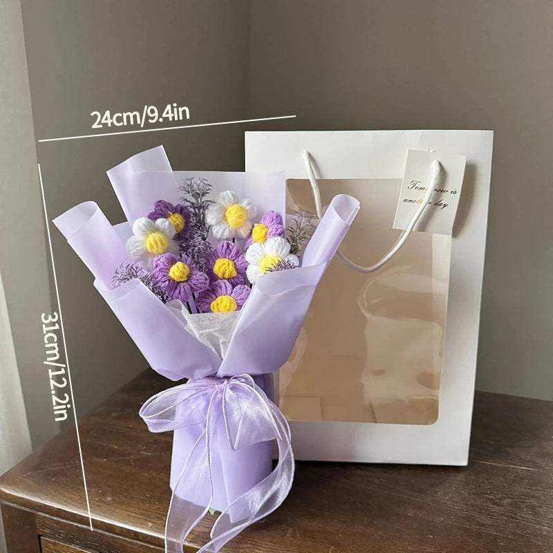 A purple handmade crochet flower bouquet tied with a white ribbon displayed in a white gift bag.