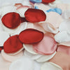 A close-up of various silk rose petals in shades of red, pink, and white scattered on a surface.
