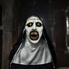 A realistic horror nun latex mask with pale white face, black veil, and glowing yellow eyes.