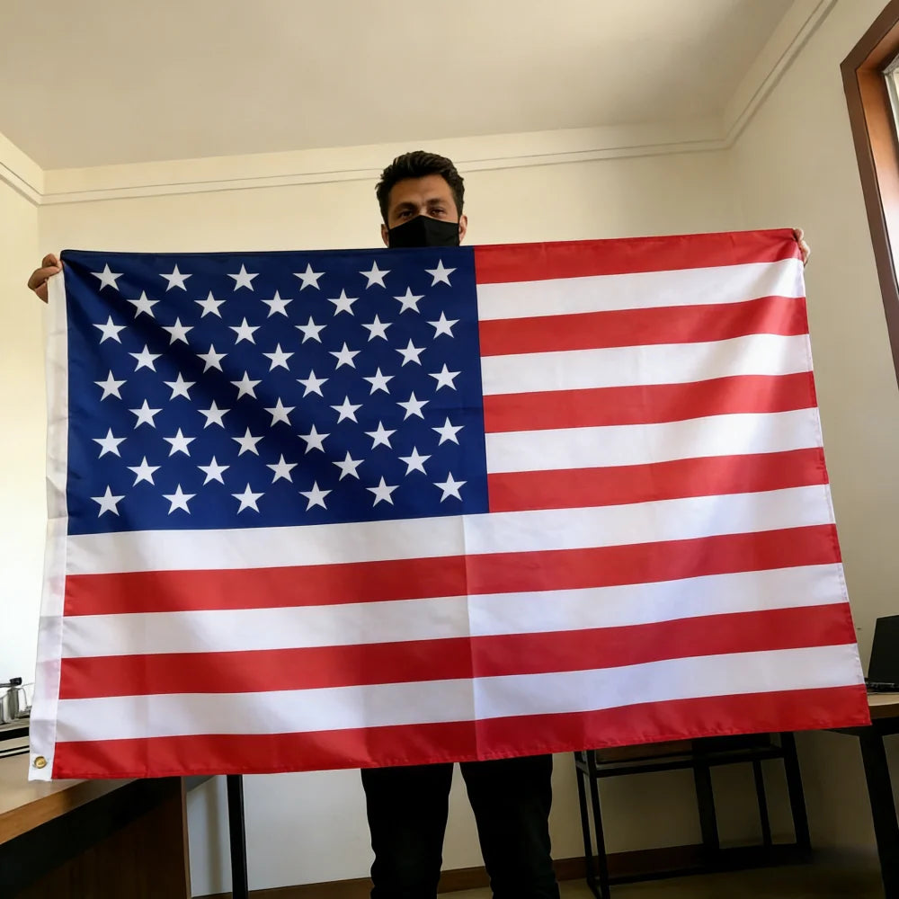 A person holds up a double-sided American flag with brass grommets indoors.
