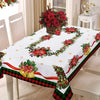 A festive red Christmas tablecloth featuring floral wreaths and plaid trim on a dining table.
