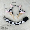 A white and black cow print headband with pink cow ears, featuring a ribbon bow detail.