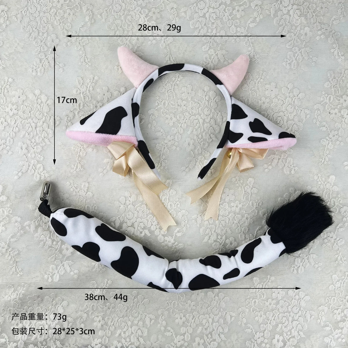 A white and black cow print headband with pink cow ears, featuring a ribbon bow detail.
