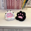A pair of pink and black silicone cat paw shaped phone stands resting on a white surface.
