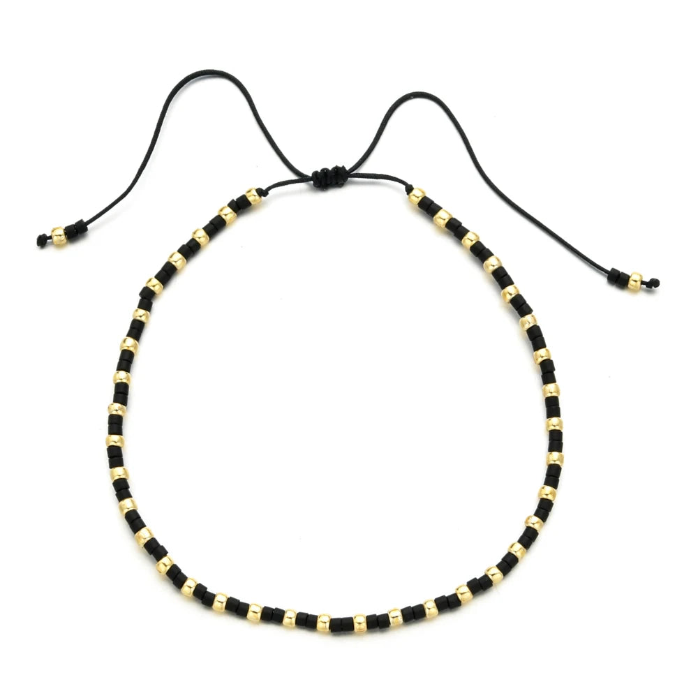 Handmade boho glass bead bracelet with adjustable cord featuring black and gold beads