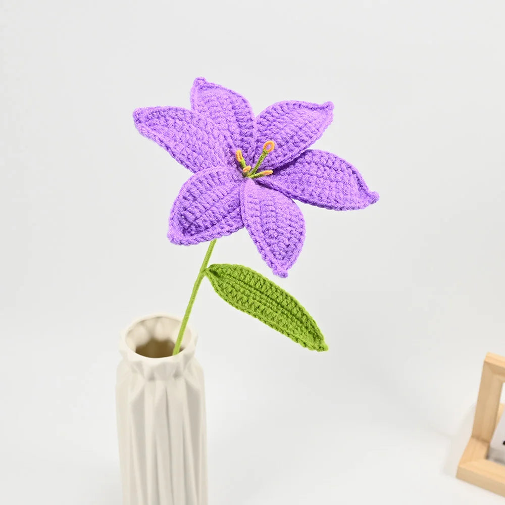 Hand-crocheted purple lily flower with a green stem in a vase