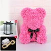 Un ours rose et duveteux en forme de rose avec un ruban noir et une décoration lumineuse LED.