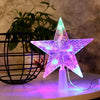 A glowing purple and green LED star shaped Christmas tree topper displayed on a white surface.
