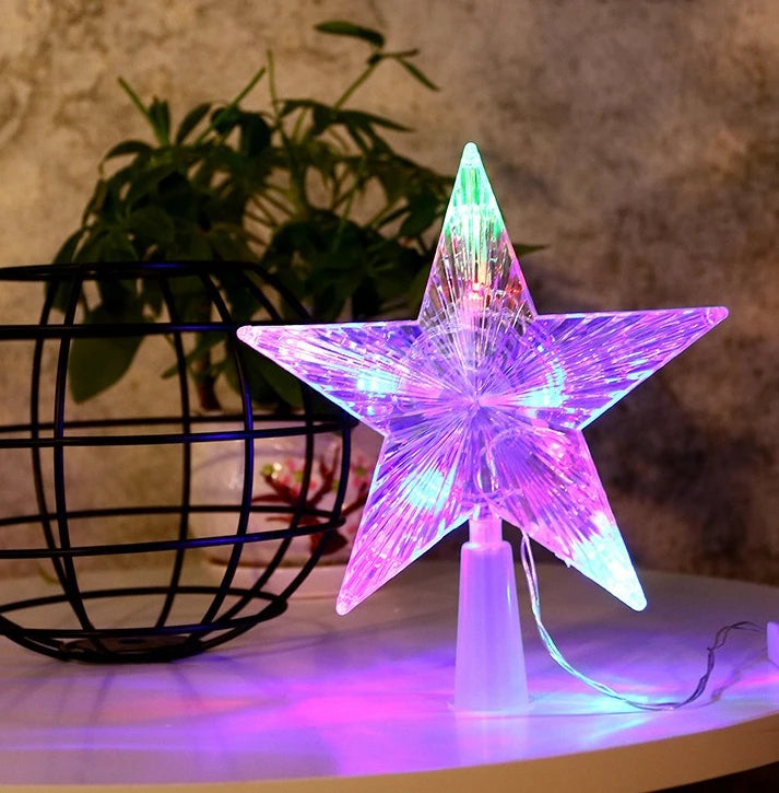 A glowing purple and green LED star shaped Christmas tree topper displayed on a white surface.