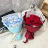 A bouquet of artificial red roses wrapped in a dark red paper and ribbon sits next to a blue bouquet.