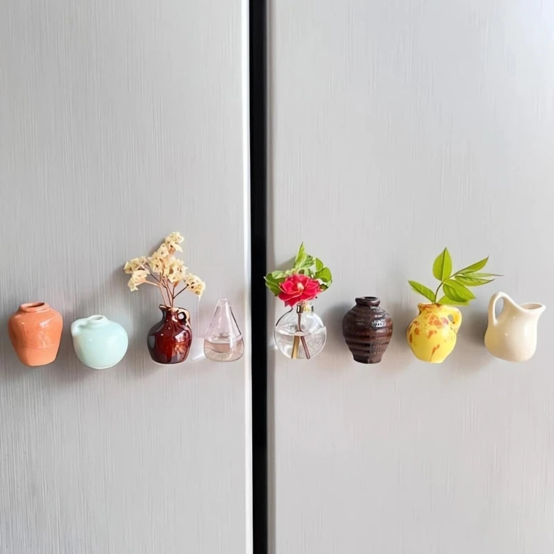 A collection of eight small ceramic vases in various earthy and pastel colors displayed on a light gray surface.