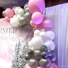 A vertical arrangement of pastel pink and white latex balloons decorated with a winter theme.