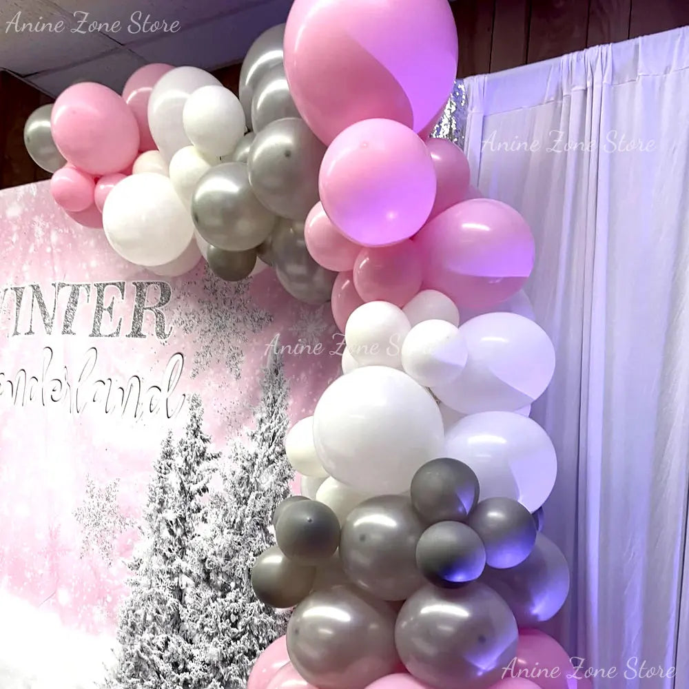 A vertical arrangement of pastel pink and white latex balloons decorated with a winter theme.