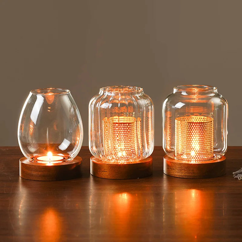 Three vintage wooden candle lanterns with glass covers glowing warmly on a dark wooden surface.