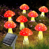 Six glowing red and white mushroom-shaped solar garden lights illuminating a grassy outdoor area.