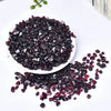 A pile of deep burgundy natural garnet crystal chips scattered on a white surface.