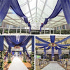Blue sheer chiffon curtains draped across a glass ceiling for an indoor event or wedding venue.