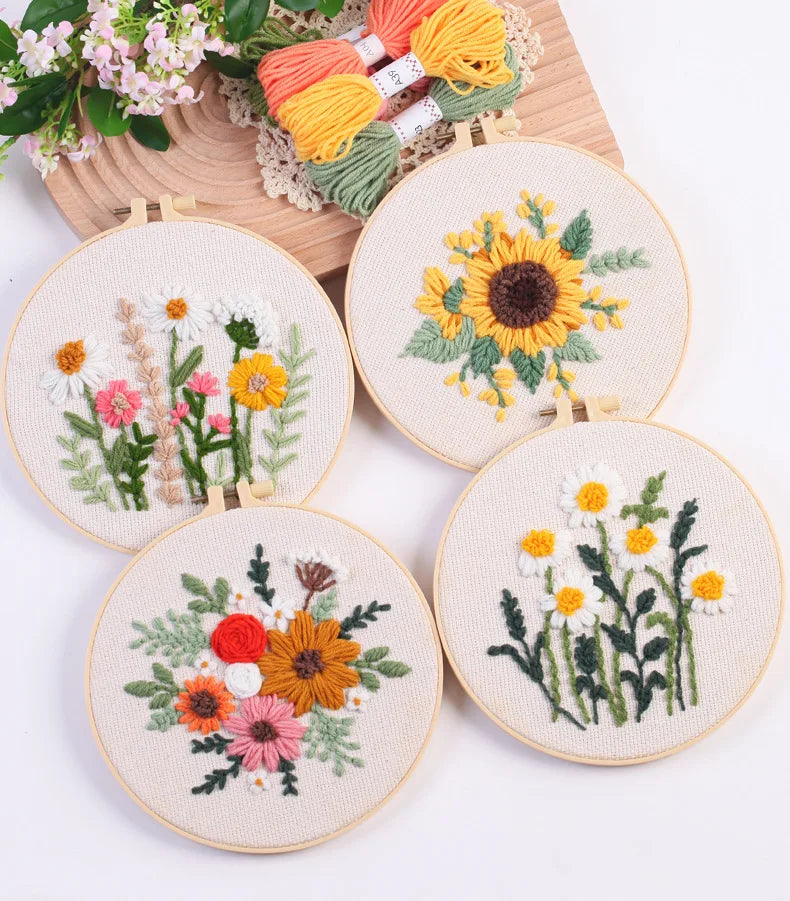 Five round embroidery pieces featuring floral designs in yellow, orange, and green thread on natural fabric.