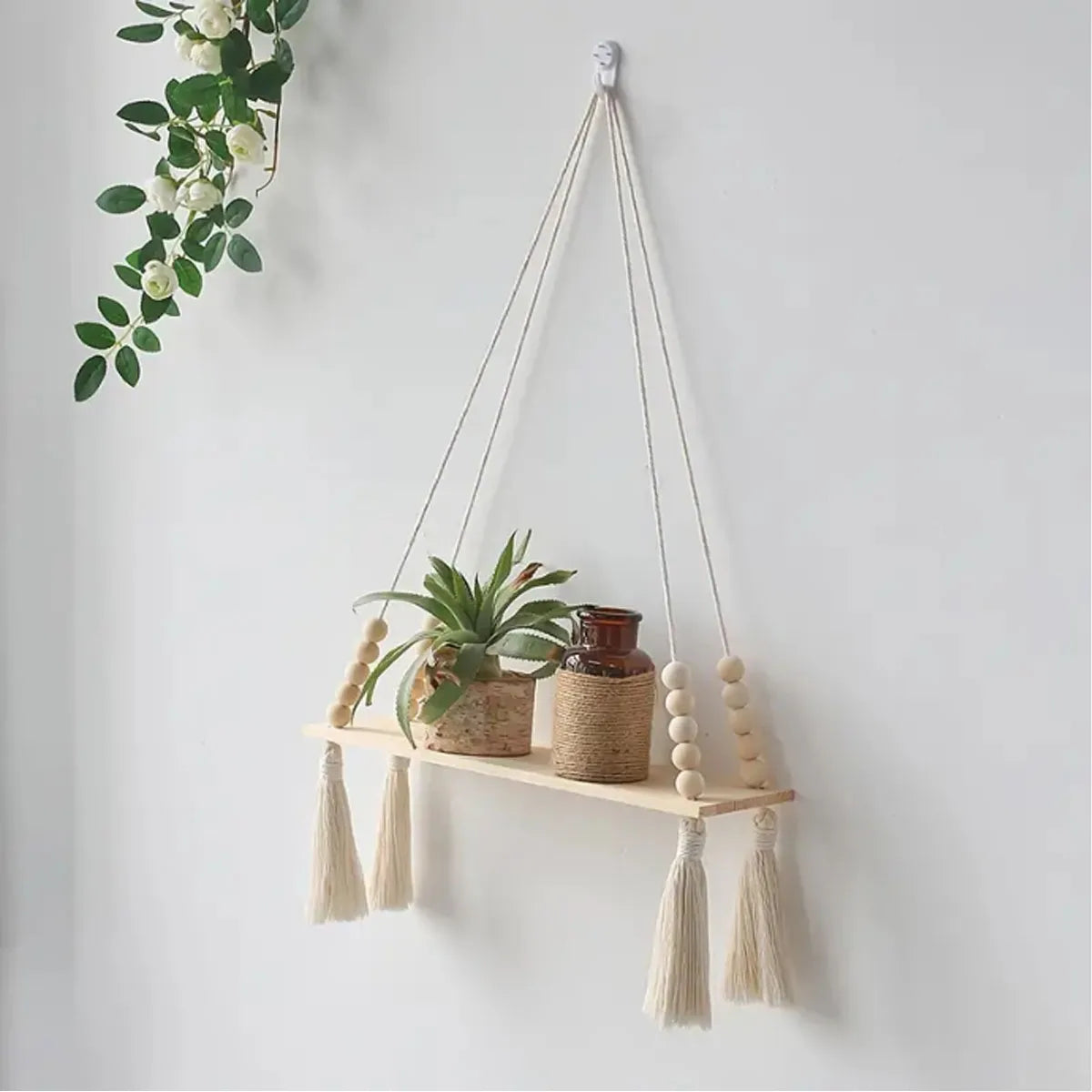 Handmade macrame wood wall shelf with tassels displaying a potted plant.
