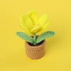 Handcrafted yellow crochet tulip flower growing in a brown crocheted pot.