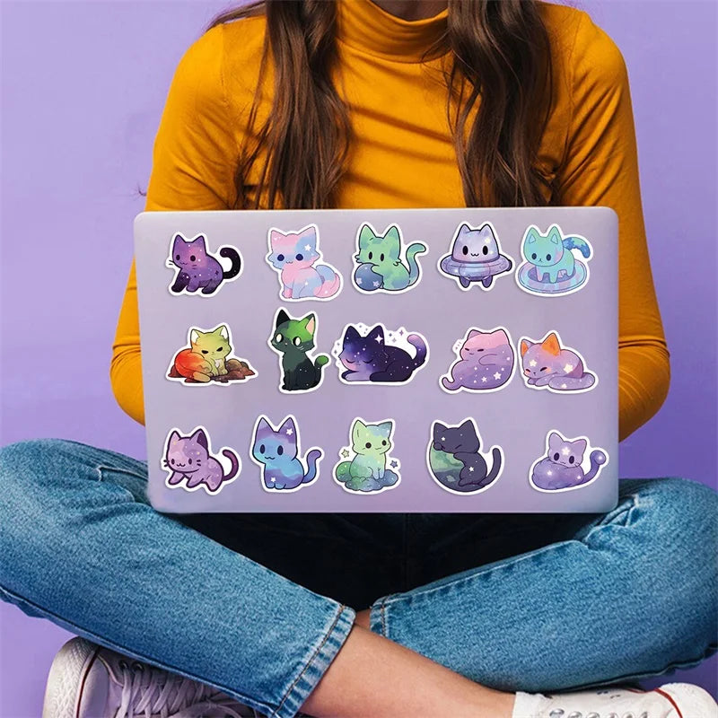 A hand holds a laptop displaying various aesthetic PVC starry sky cat stickers for scrapbooking