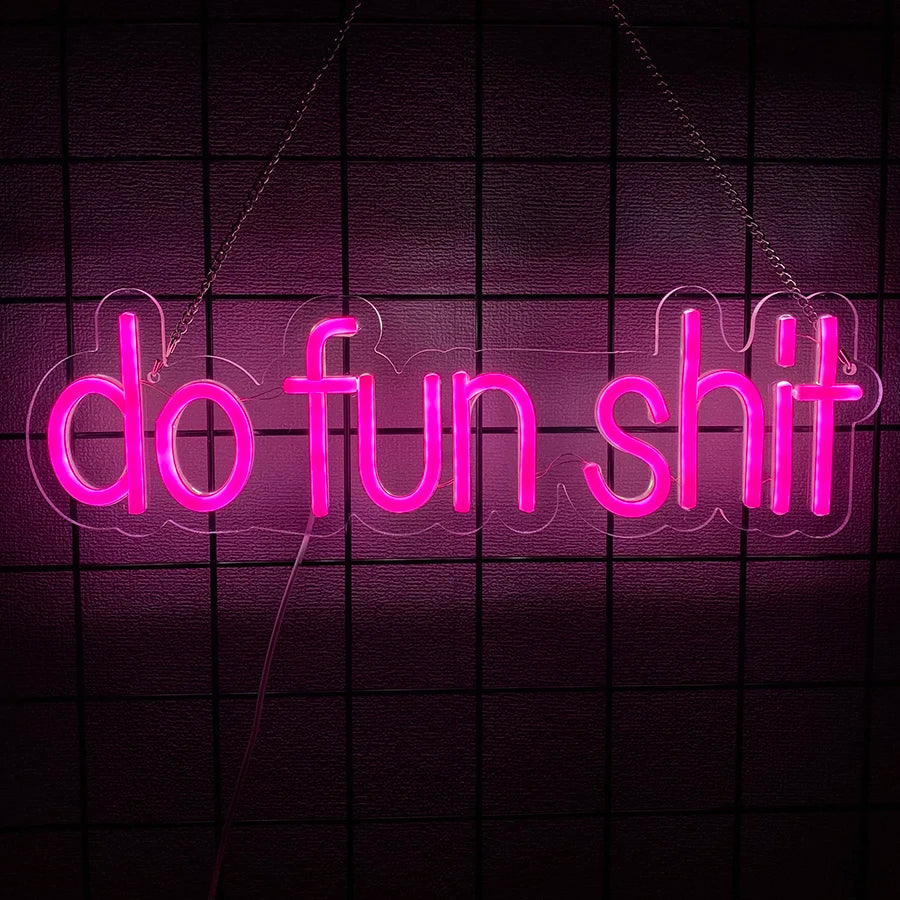 Neon pink sign spelling out do fun shit hanging against a dark grid background