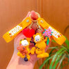 A hand holds a yellow keychain pendant featuring Garfield cartoon characters, including a bear and a cat.